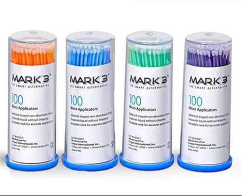 Four Mark 3 micro applicator tubes in orange, blue, green, and purple, arranged in a row against a white background.
